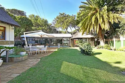 a backyard with a table and chairs and a palm tree at Unique Thatch Home in Champagne area in Pinelands in Cape Town