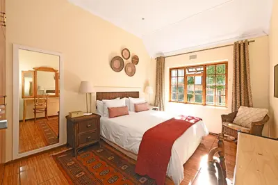 a bedroom with a large bed and a mirror at Unique Thatch Home in Champagne area in Pinelands in Cape Town
