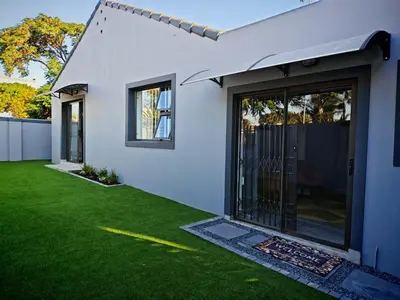 a white house with a yard with green grass at Kubata Diame B&B in Cape Town