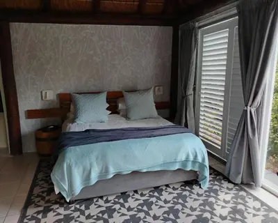 a bedroom with a bed and a window at The Thatched Cottage in Eversdal