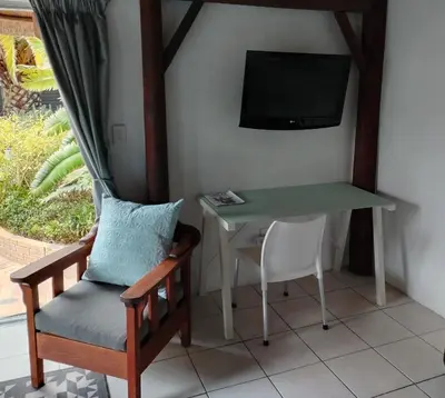 a room with a table and a chair and a tv at The Thatched Cottage in Eversdal