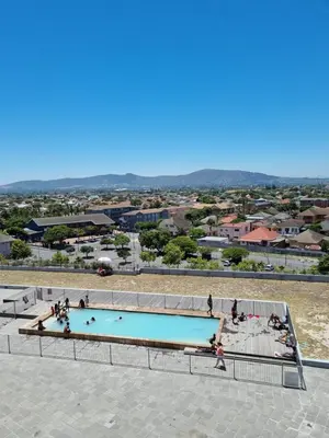 a swimming pool with people sitting around it at Comfy 1 Bedroom Flat in Thornton