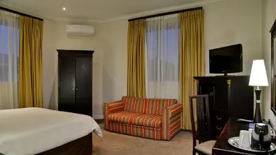 a hotel room with a bed and a chair at Cumberland Hotel & Conference Centre Worcester in Worcester