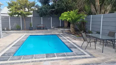 a swimming pool in a backyard with a table and chairs at Frankie's Nest in Cape Town