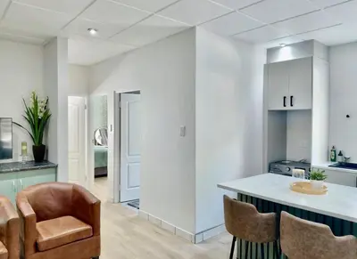 a kitchen with white walls and a counter and chairs at Finch Nest Self Catering in Paarl