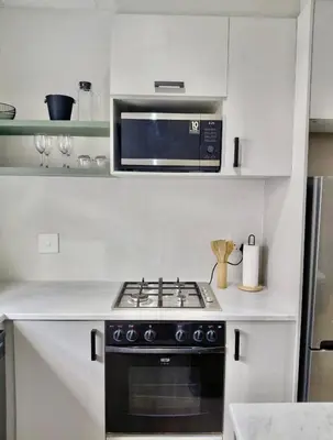 a kitchen with a stove and a microwave at Finch Nest Self Catering in Paarl