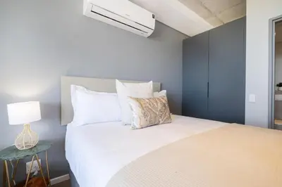 a bedroom with a white bed and a blue wall at 805 Riverlands - Lux Studio Apartment in Cape Town