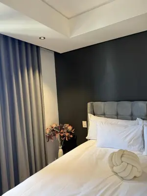 a bedroom with a white bed with a black wall at Enzo Stay -The Matrix 505 , Century City in Cape Town