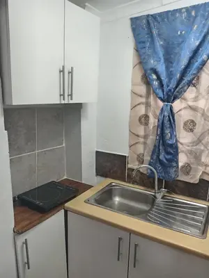 a kitchen with a sink and a blue curtain at One Bed Room Apartment 1A in Cape Town