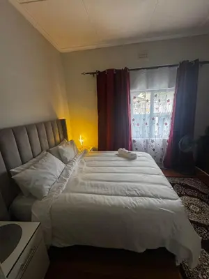 a bedroom with a large white bed and a window at kitty guest house in Bellville
