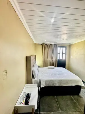 a room with a bed and a table in it at kitty guest house in Bellville