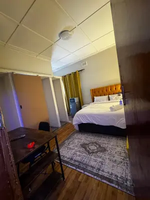 a bedroom with a bed and a desk and a table at kitty guest house in Bellville