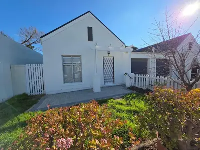 a white house with a white fence and some flowers at 2 Bedroom house at Tweespruit - Pet friendly in Stellenbosch