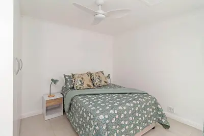a white bedroom with a bed and a ceiling fan at The Woodbridge Hideaway in Cape Town