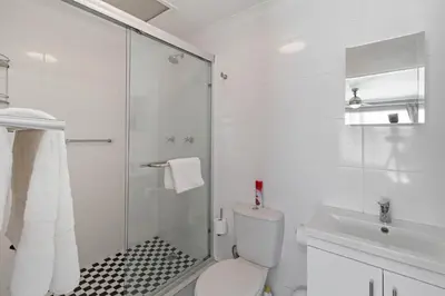 a bathroom with a shower and a toilet and a sink at The Woodbridge Hideaway in Cape Town