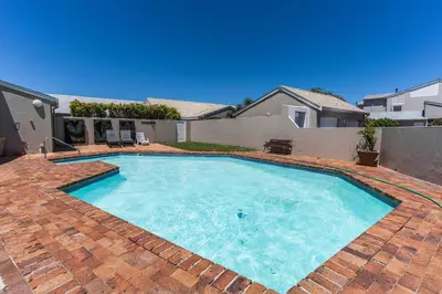 a large swimming pool on a brickickedicked yard at The Woodbridge Hideaway in Cape Town