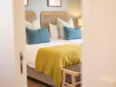a bedroom with a bed with blue and white pillows at Cornercade | Unit 1 in Hermanus