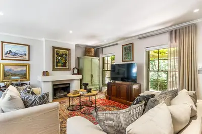 a living room with white furniture and a tv at Pepler House in Franschhoek