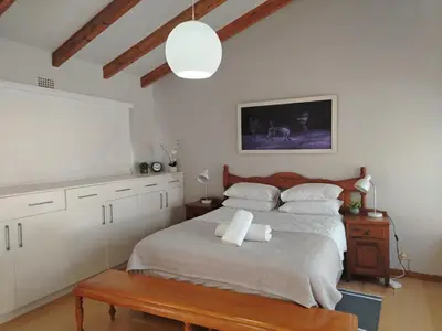 a bedroom with a large bed and a table at Art House on Main in Hermanus