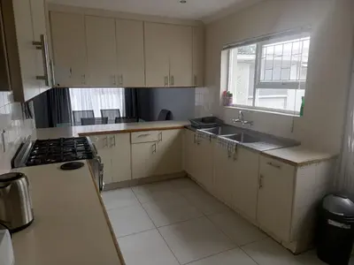 a kitchen with white cabinets and a sink and a window at Capetown Adilo Villa in Cape Town
