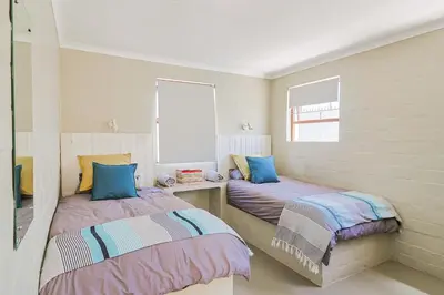 two twin beds in a room with two windows at Herringbone with Wood-Fired Hot Tub in Hermanus