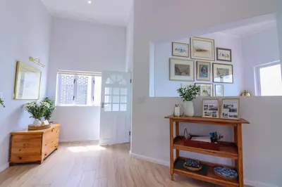 a living room with white walls and a wooden floor at Blou Huis in Hermanus