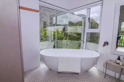a white bath tub in a bathroom with a window at Blou Huis in Hermanus