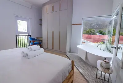 a white bedroom with a tub and a sink at Blou Huis in Hermanus