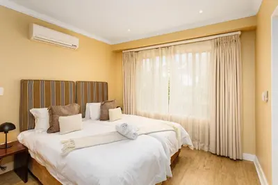 a bedroom with a large white bed with a window at Pearl Valley Golf Estate, Cedar Point 4A in Simondium