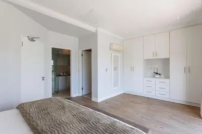 a white bedroom with a bed and white cabinets at Pearl Valley Golf Estate, Cedar Point 4A in Simondium