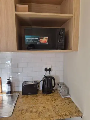 a kitchen counter with a coffee maker and a microwave at Secure Modern stay at 41 on Kennington in Parklands