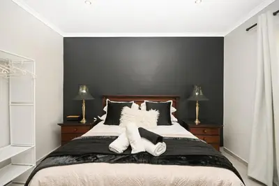 a bedroom with a large bed with two lamps at Velvet & Bloom Cottage in Durbanville in Oakdale