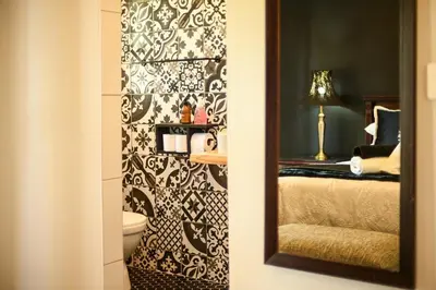 a bathroom with a mirror and a bed in a room at Velvet & Bloom Cottage in Durbanville in Oakdale
