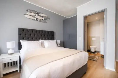 a bedroom with a large bed with a black headboard at 827 Riverlands - Studio Apartment with Parking in Cape Town