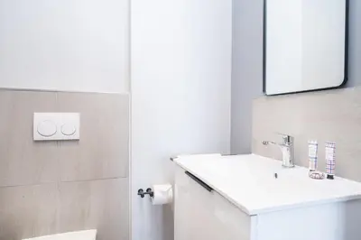 a white bathroom with a sink and a mirror at 827 Riverlands - Studio Apartment with Parking in Cape Town