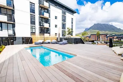 an apartment patio with a swimming pool and a building at 827 Riverlands - Studio Apartment with Parking in Cape Town