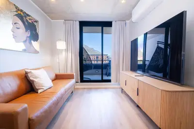 a living room with a couch and a large television at 312 Riverlands - Lux 2 bedroom Apartment in Cape Town