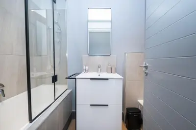 a white bathroom with a sink and a shower at 312 Riverlands - Lux 2 bedroom Apartment in Cape Town