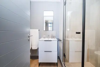 a white bathroom with a sink and a mirror at 312 Riverlands - Lux 2 bedroom Apartment in Cape Town