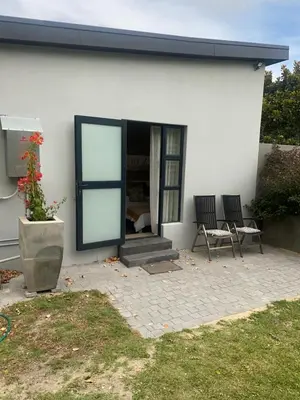 a white house with two chairs in front of it at Living Lite in Kleinmond