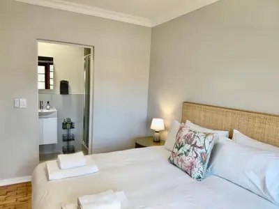 a bedroom with a bed with white sheets and a mirror at The Botanic Venus in Paarl