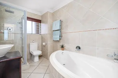 a bathroom with a tub and a toilet and a sink at Sea Spray Views in Cape Town