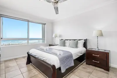 a white bedroom with a bed and a window at Sea Spray Views in Cape Town