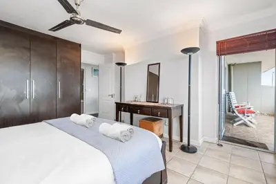 a bedroom with a bed and a desk and a mirror at Sea Spray Views in Cape Town