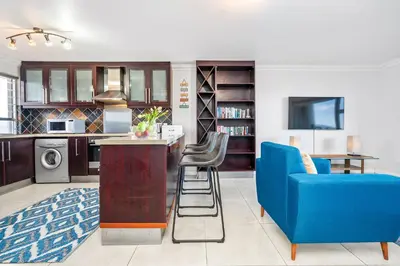 a kitchen with a blue couch and a blue chair at Sea Spray Views in Cape Town