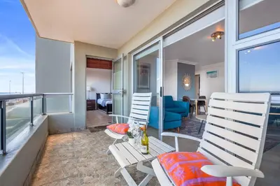 a balcony with two chairs and a table at Sea Spray Views in Cape Town