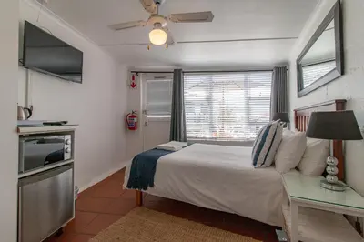 a bedroom with a bed and a table and a window at TwentyFour 17 Inn in Hermanus