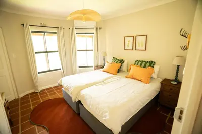 a bedroom with a bed with orange and green pillows at Kerala Cottage - farm charm inspired self-catering