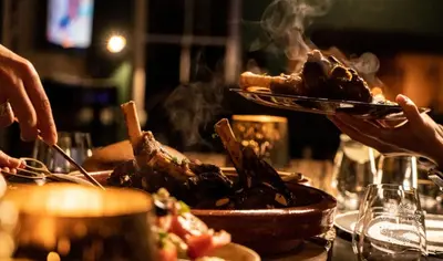 a person holding a plate of food on a table at Drakenskloof - Exclusive-Use Mountain Homestead