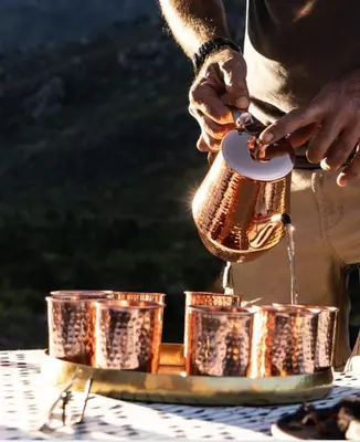 a person is pouring water into a metal object at Drakenskloof - Exclusive-Use Mountain Homestead